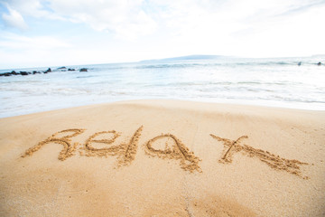 The word relax written in sand at beach