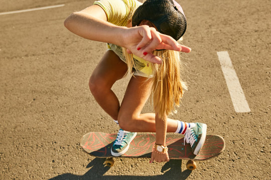Girl doing a skateboard trick skateboarding on a parking in the sunset in Sochi