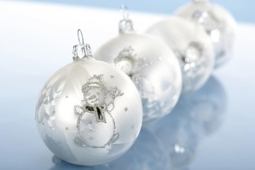 Four white Christmas ornaments decorated with snowmen, balls in a row