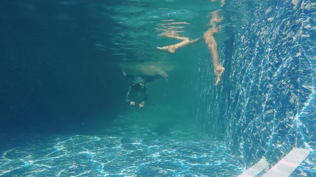 Man in suit swims under water with piece of paper in his mouth