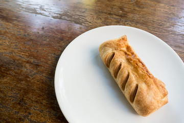 Topdown view of english pastry pie on white dish on brown table.