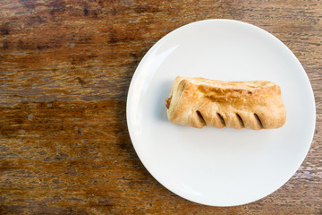 Topdown view of english pastry pie on white dish on brown table.