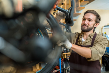 Professional repairman with spanner fixing detail of bicycle wheel