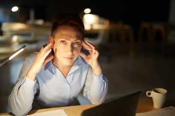 Tired woman trying to concentrate while working at night in office