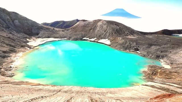 Panorama of the slope of Ebeko volcano on Paramushir Island. Acid lake in the crater of the volcano and the top of the mountain behind the strait covered by fog. Kuril Islands, Russia
