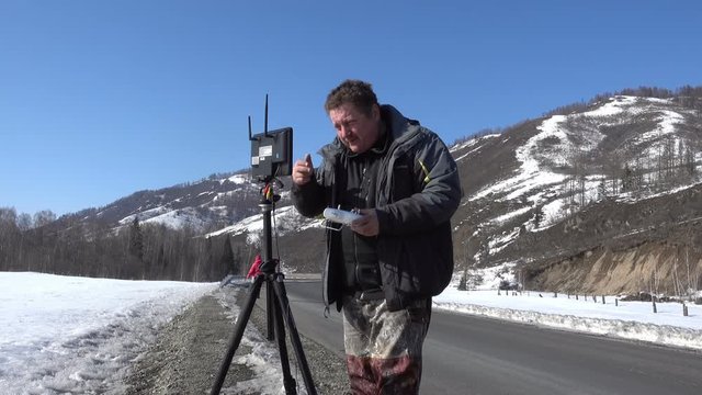 man with remote control pult for copter drone on the winter mountain road
