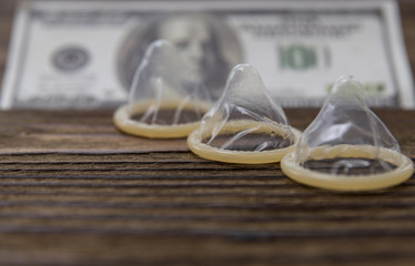 Three condoms on a background of a hundred dollars bills. sex for money, condom, selling love.