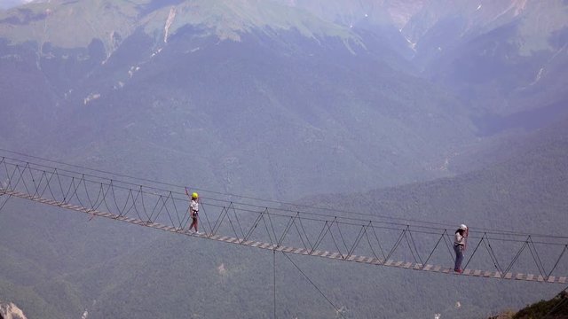 The crossing of the abyss in the mountains .People go on rope bridge across the chasm.Extreme tourism.