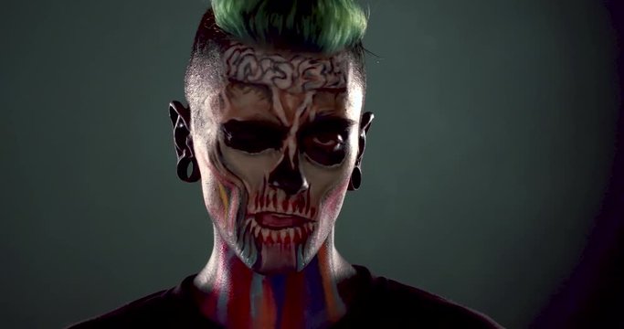 Man with scary skeleton face in studio. Halloween face art, zombie makeup on mans face.