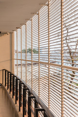 Grill wall with orange light that cast shadow on the white wall of hotel corridor in Chiang Mai, Thailand.