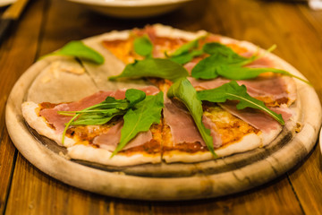 Parma Ham Pizza on rounded wooden plate at the restaurant in Chiang Mai, Thailand.