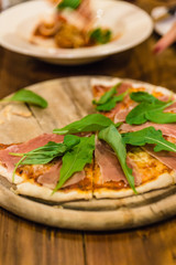 Parma Ham Pizza on rounded wooden plate at the restaurant in Chiang Mai, Thailand.