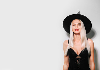 blonde girl in a halloween witch costume on a white background