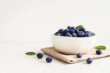 Juicy and fresh blueberries with green leaves on white bowl. Healthy eating