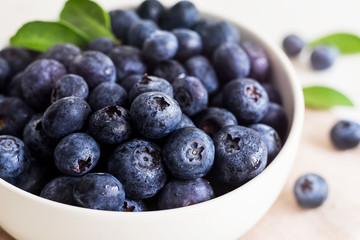Juicy and fresh blueberries with green leaves on white bowl. Healthy eating