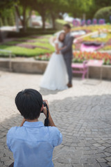 wedding photographer takes pictures of the bride and groom in park, the photographer in action.