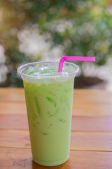 Iced green tea latte on wood table in cafe.