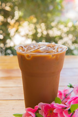 ice coffee in the glass, ice coffee on wood table over bokeh background.
