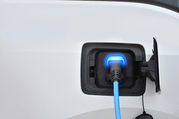 Charging an electric vehicle. Blue charging indicator light. Fuel of the future.