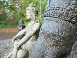 Fototapeta na wymiar Shiva und Ganesha Statue im Profil aus Stein sitzend auf Holzplattforn