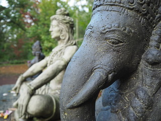 Obraz premium Shiva und Ganesha Statue im Profil aus Stein sitzend auf Holzplattforn