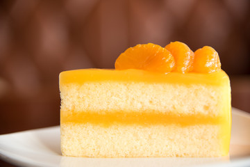 Orange cake on plate with blur brown background