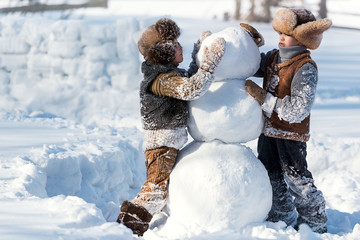 Children shape the snowman in the backyard of the house