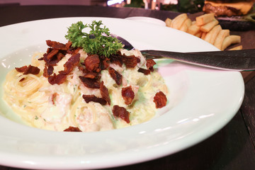 creamy carbonara spaghetti with bacon on white dish