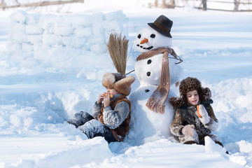 Children shape the snowman in the backyard of the house