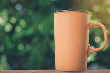 Obraz premium Coffee cup on wooden table over bokeh from tree background vintage style.