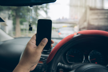 Man sitting in the car and holding a touch phone with  black screen.