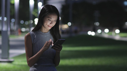 Fototapeta premium Woman using mobile phone in the city at night