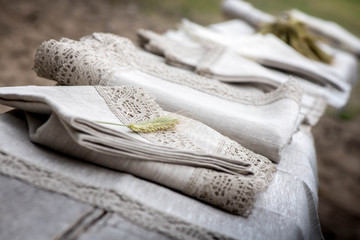 Shot of linen towels, tablecloths, napkins with crochet white and grey lace trim on a wooden bench