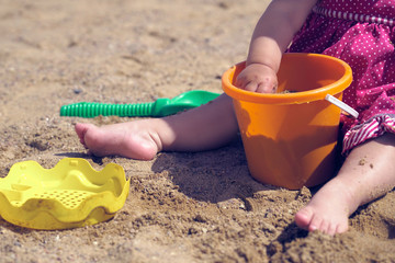 Close-up of the hand of a little girl playing with sand in the sandbox.