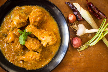 Massaman chicken in plate black ,pepper dry coriander, lemon grass, garlic, shallots.  placed on a wooden table Old brown.,spicy muslim curry eaten with rice or roti