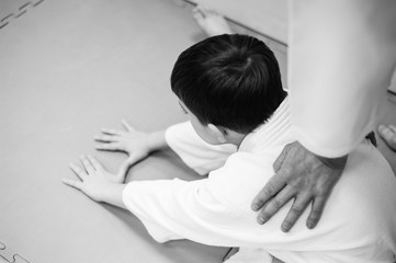 A boy in a kimono has an aikido training with a coach