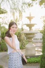 Happy woman use smart phone outdoor at garden, Tha  beauty woman call phone and smile.