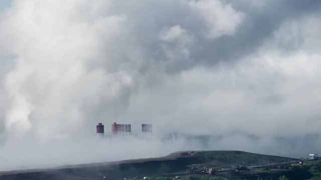 The atmosphere is tainted by air pollution as smoke and smog envelop the landscape, emanating from industrial activities, particularly a coal power plant in the morning mist