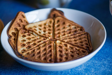 Macro shot of just cooked, delicious, tasty and hot yogurt pancakes with strawberry sauce on yellow and white plates in kitchen, next to stove. Dinner is ready. Sweet golden brown waffles with jam