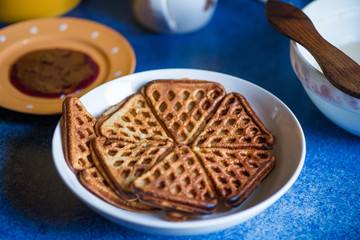 Macro shot of just cooked, delicious, tasty and hot yogurt pancakes with strawberry sauce on yellow and white plates in kitchen, next to stove. Dinner is ready. Sweet golden brown waffles with jam