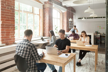 Young casually dressed employees at work in coworking office. Corporate team working on laptops and...