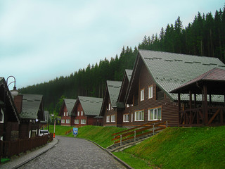 Fototapeta na wymiar Wooden cottages are at mountain resort near forest under blue sky