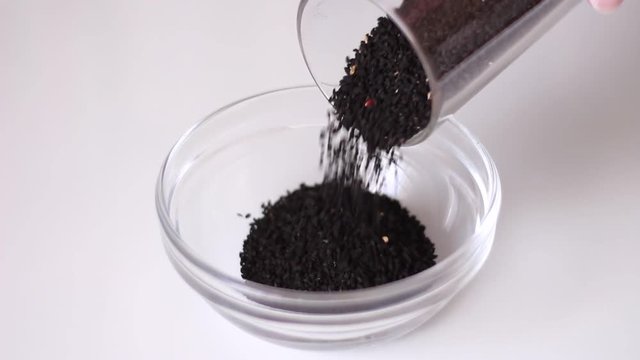 Pouring glass can with black cumin seeds