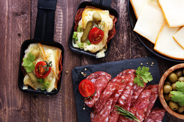 Delicious traditional Swiss melted raclette cheese on diced boiled or baked potato served in individual skillets with salami..