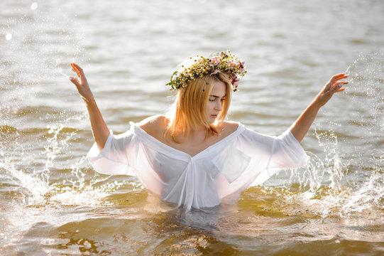 Girl In White Shirt And Floral Wreath Standing In Water