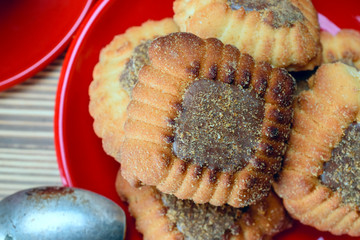 cookies on a red plate and coffee in a red mug standing on a wooden background 