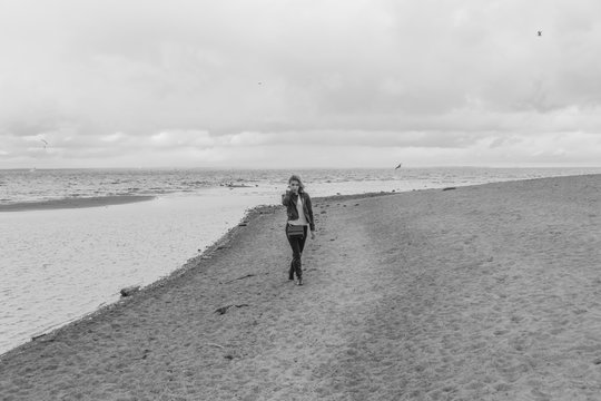 black and white, on the beach on a cloudy day walks an attractive girl