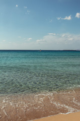 Greek beach with turquoise water and someone doing windsurf in the distance