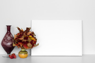 Mock up poster in neutral interior with  red maple leaves and vase. Blank white canvas for design.