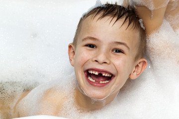 Happily laughing child boy taking a bath. Milk teeth missing